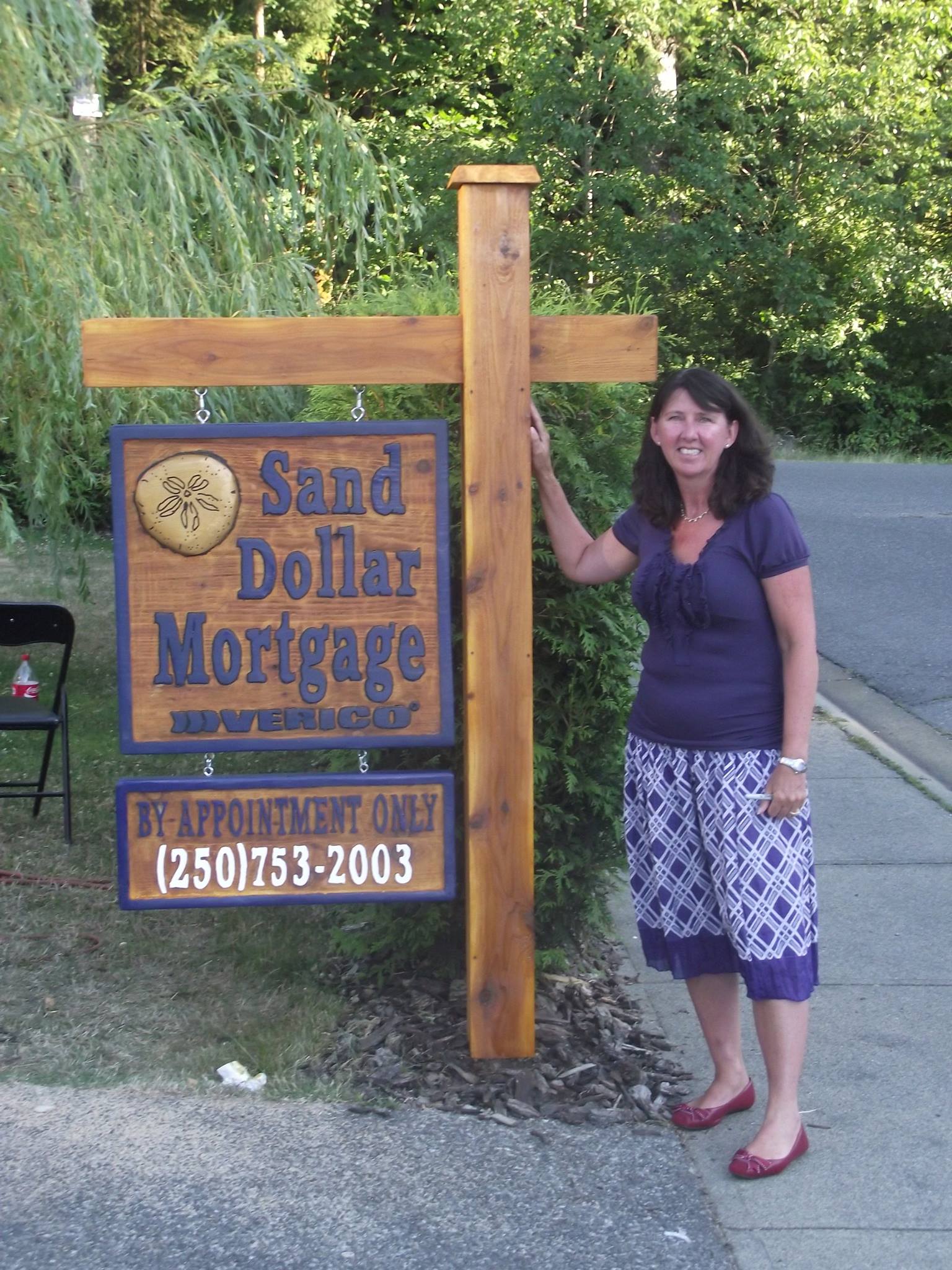 Owner near cedar sign, Sand Dollar Mortgage.
